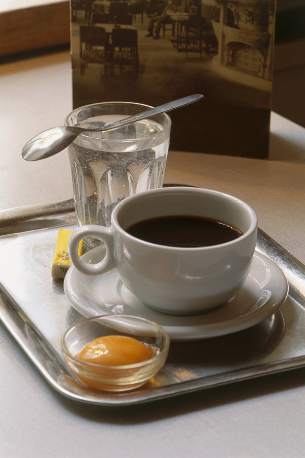 Kaisermelange, coffee with egg yolk, sugar and cognac, served with glass of water on serving tray, a coffee specialty from Austria